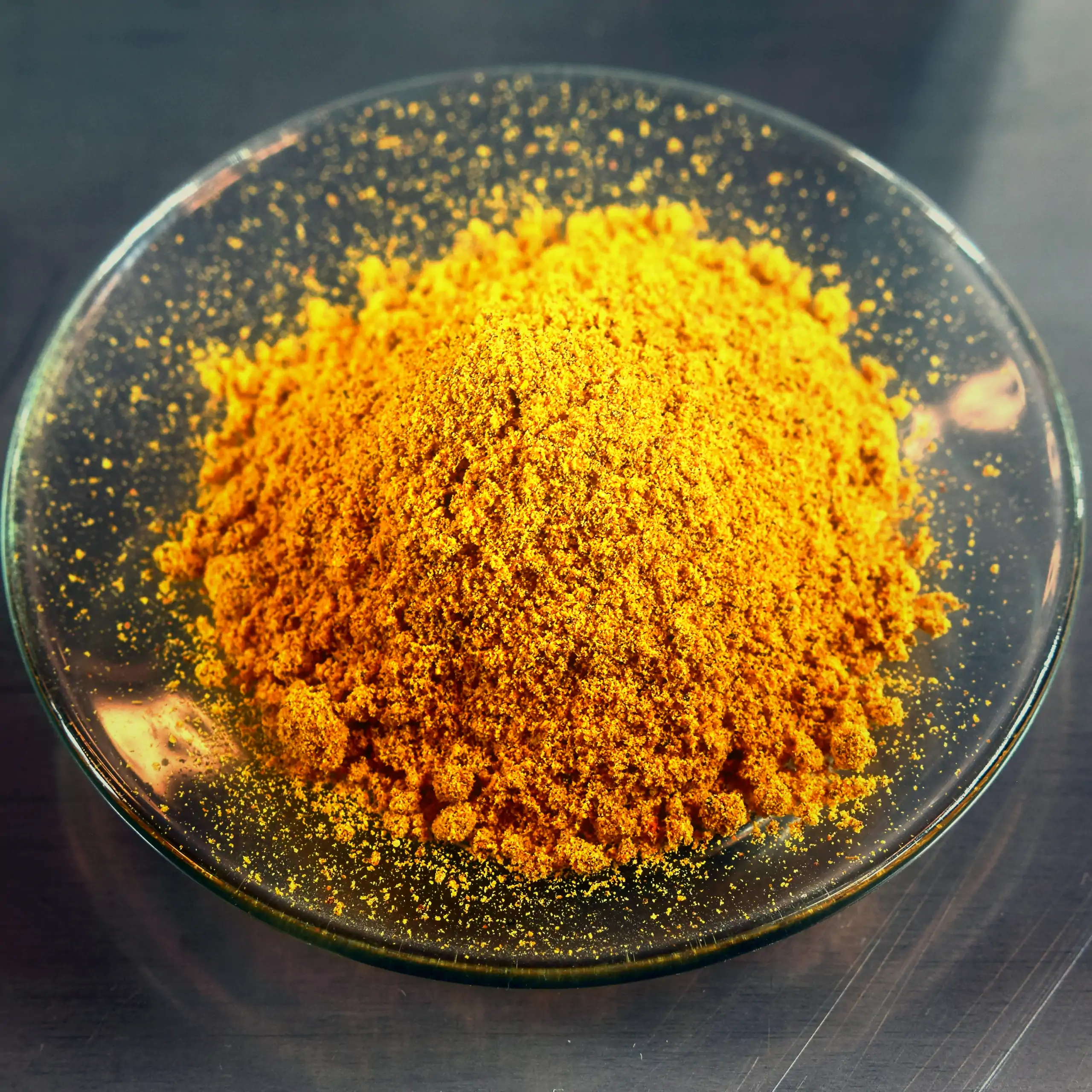 Alternatives Vorschaubild der Galerie für Körrie M25 Gewürzmischung: Eine leuchtend goldgelbe, fein gemahlene vollmundige Würzmischung, kunstvoll auf einem transparenten Glas-Teller angehäufelt arrangiert, präsentiert auf einer metallischen Oberfläche für