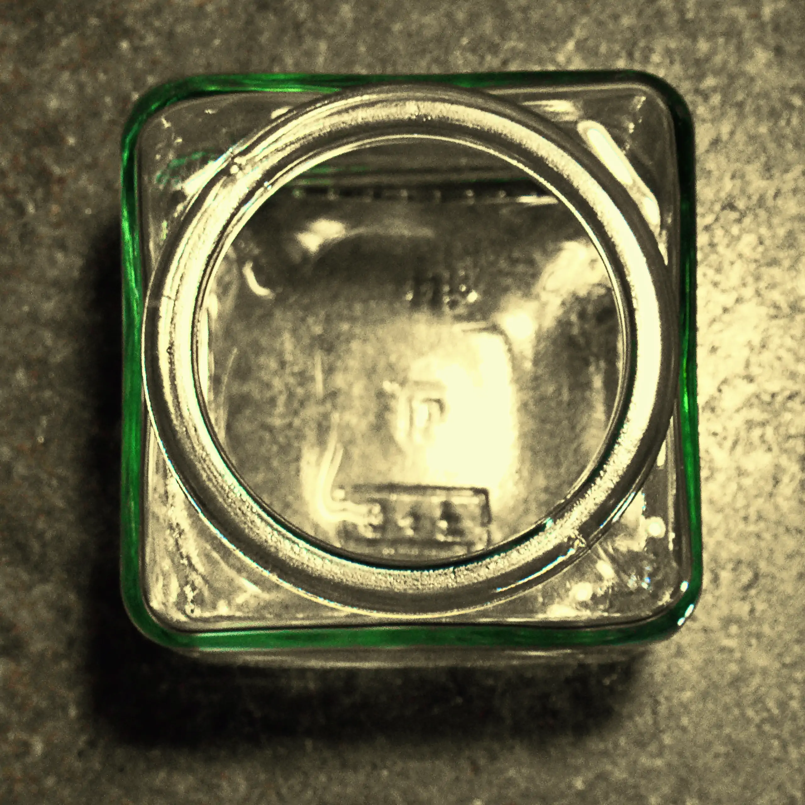 Zusätzliches Bild des Körrie-Korken-Glas (Körrie KKG): Ein offenes, quadratisches Glasgefäß von oben präsentiert, mit klarer Geometrie bei platzsparender quadratischer Grundplatte, mit leicht grünlicher Tönung des Glases am Rand, stehend auf einer dunklen