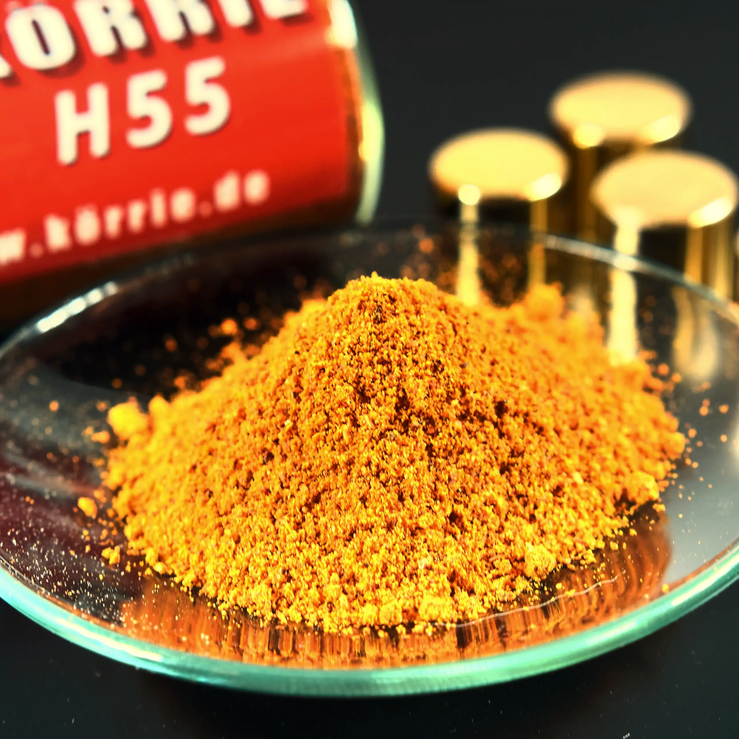 Zusätzliches Bild der Körrie H55 Gewürzmischung: Eine leuchtend orange-goldene, fein gemahlene, herzhafte Gewürzmischung in einer transparenten Glasschale, mit Hintergrund ein Gewürzglas, etikettiert mit "KÖRRIE H55" und der Website www.körrie.de, sowie g