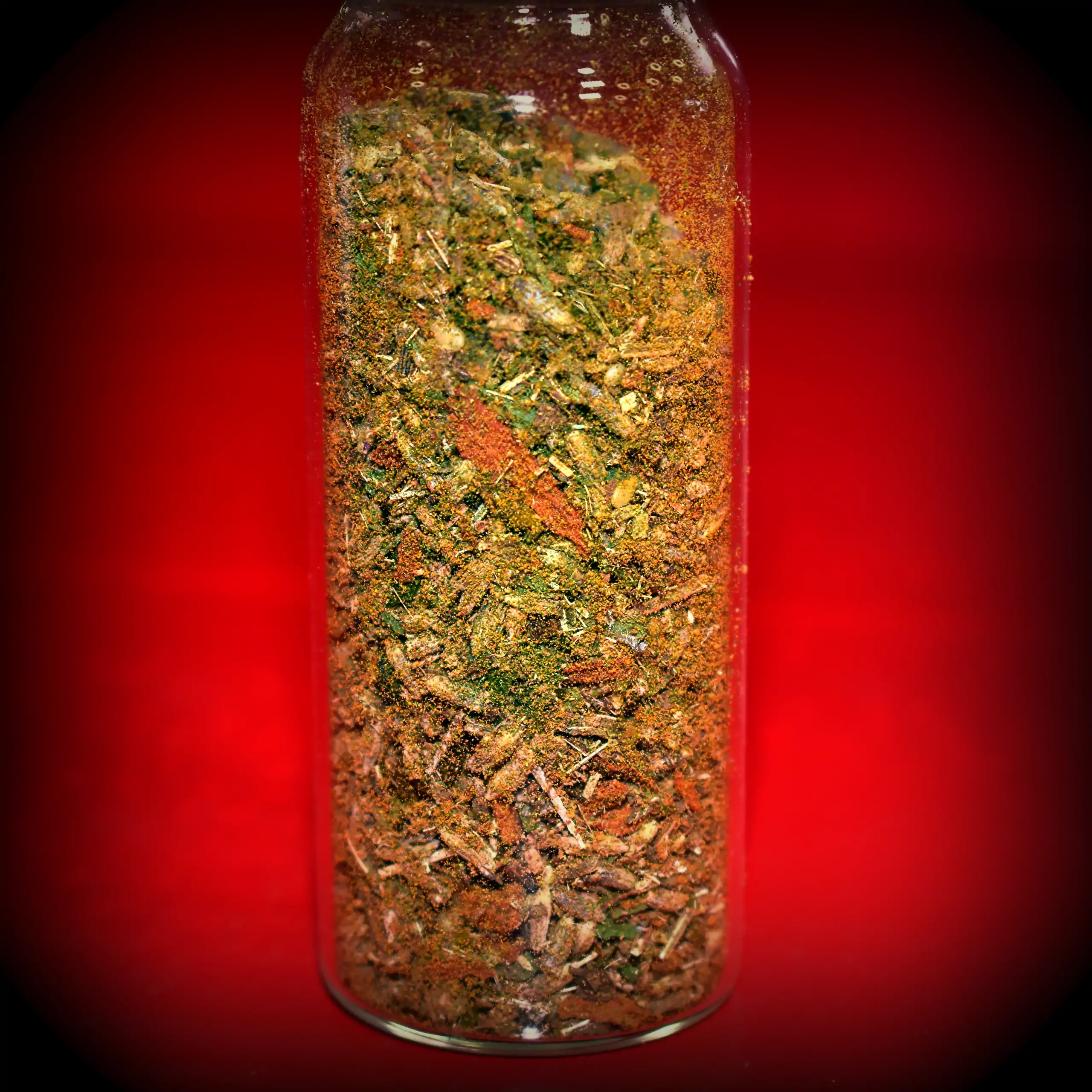 Zusätzliches Bild der sanften Gewürzmischung Körrie FLX: Eine transparente, zylindrische Glasflasche, gefüllt mit farbenfroher, grob geflockter Kräuter- und Gewürzmischung, rote Beeren, grüne Blätter, lavendelblaue Blüten und würzige Flocken und rotbraune